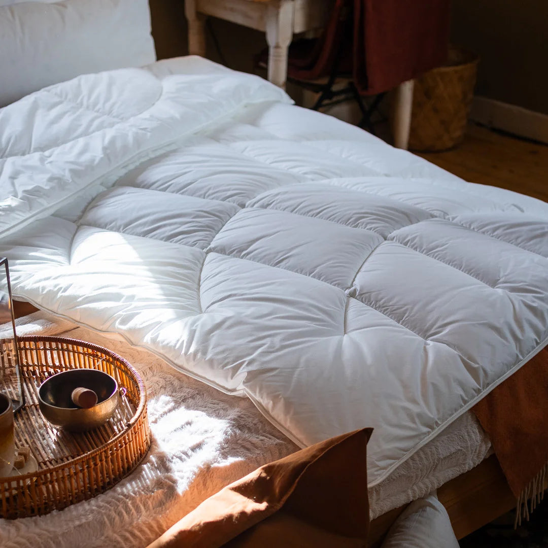 Weiße Paradies Runa Bio Ganzjahresdecke mit Bodyform Steppung liegt sanft auf einem Bett ausgebreitet