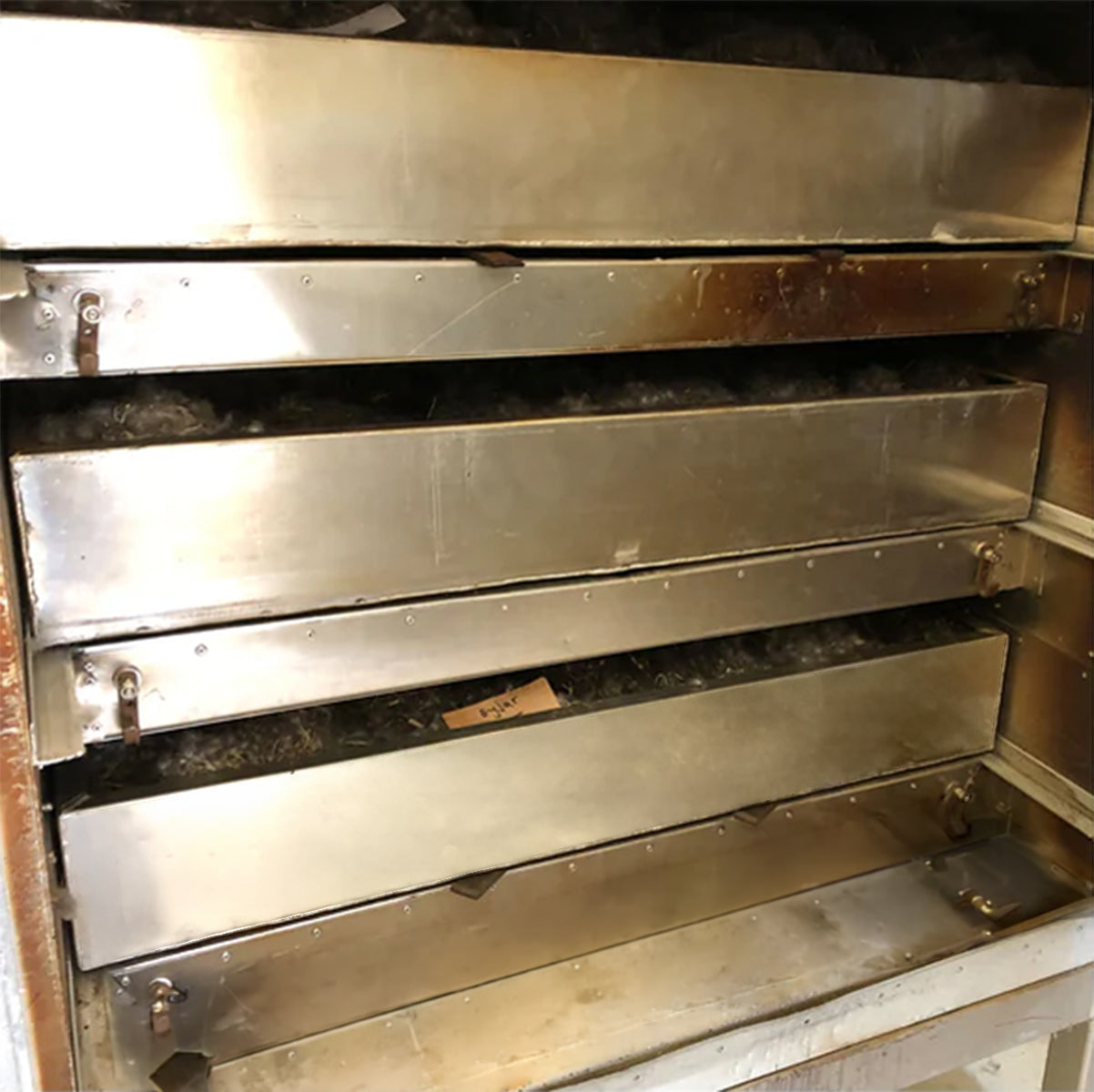 Große, gestapelte Metallschubladen einer Trocknungsanlage für die Verarbeitung von Eiderdaunen.