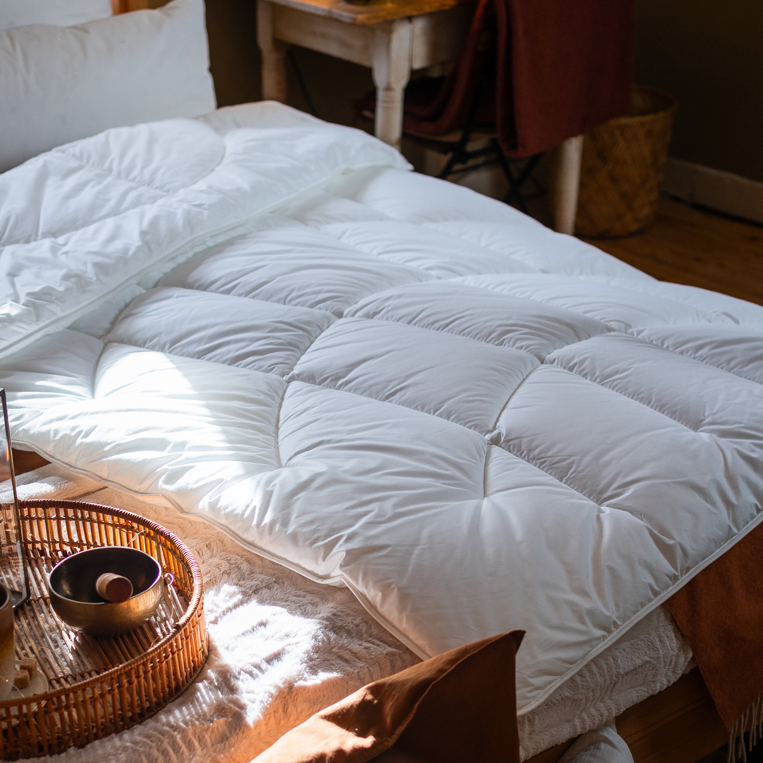 Weiße Paradies Runa Bio Ganzjahresdecke mit Bodyform Steppung liegt sanft auf einem Bett ausgebreitet