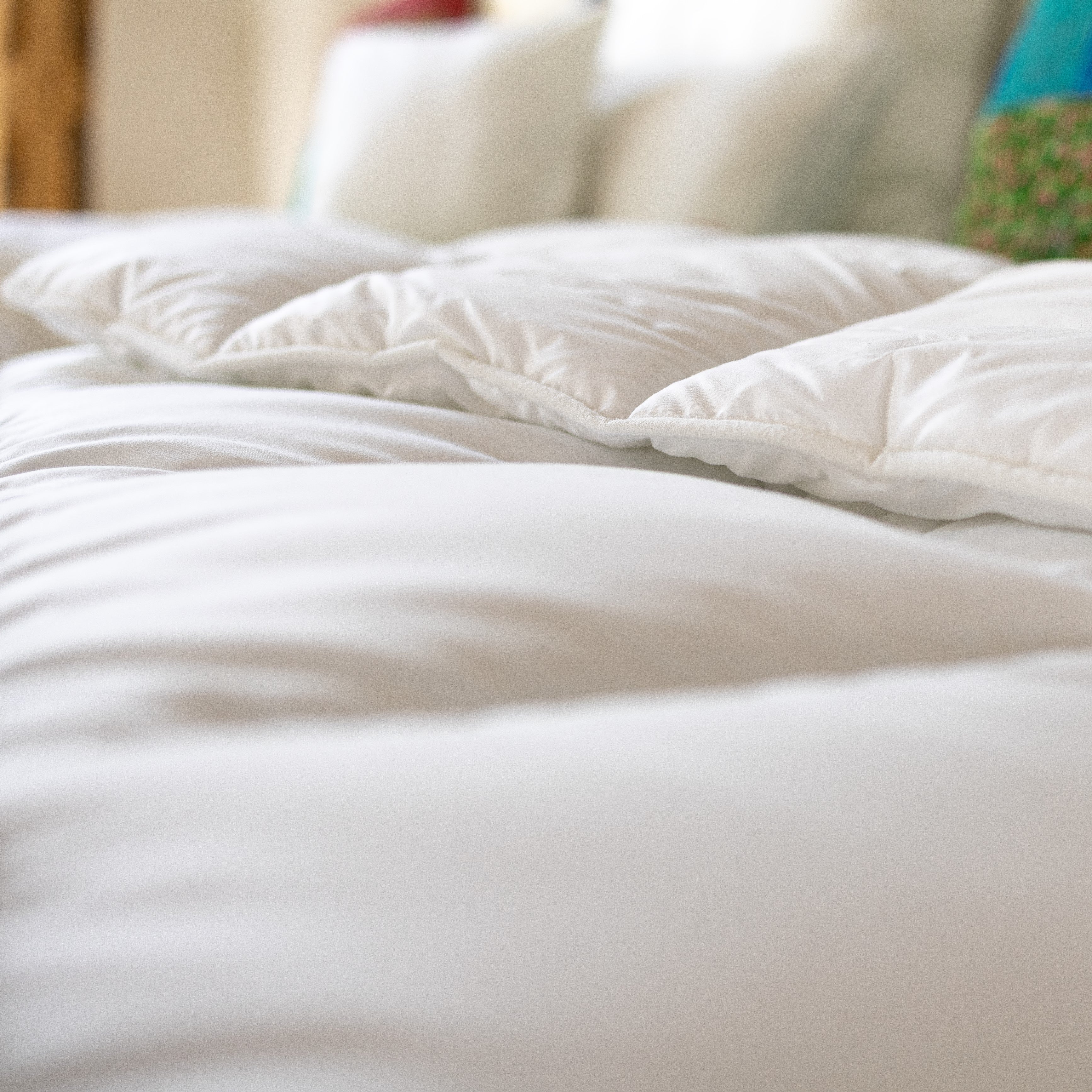 Nahaufnahme der weißen, gefalteten Renova Ganzjahresbettdecke mit sichtbaren Steppnähten und weichem Stoff.