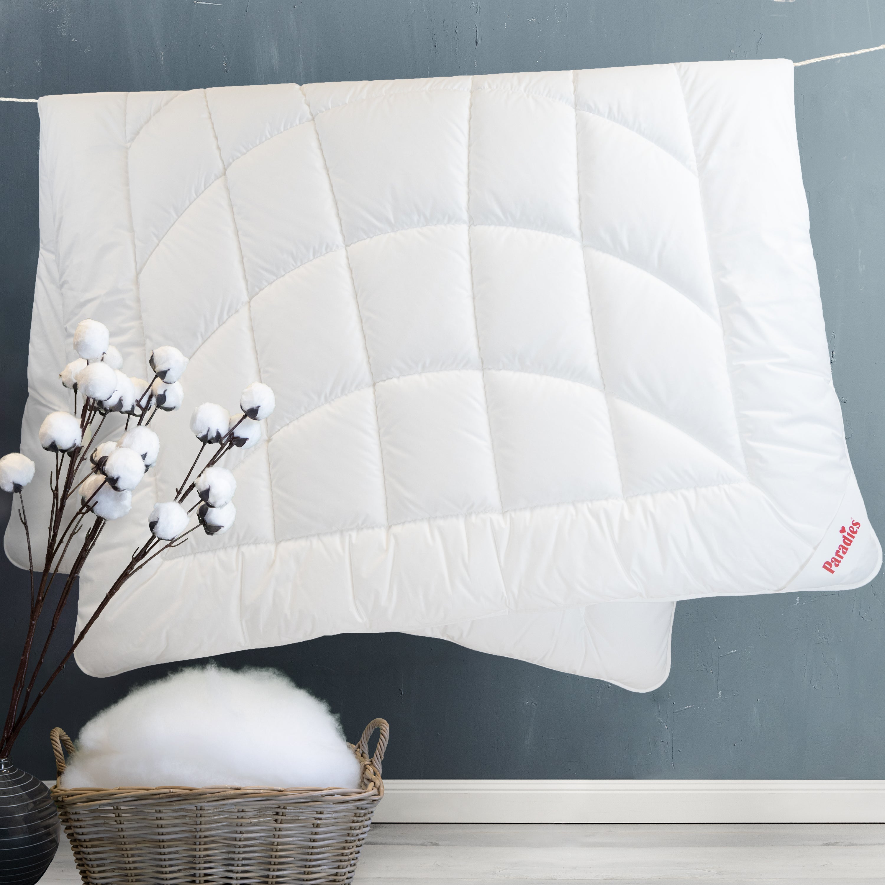 Runa winterwarm hängend auf einer Wäscheleine mit einer Baumwollpflanze und einem Flechtkorb mit Fasern 